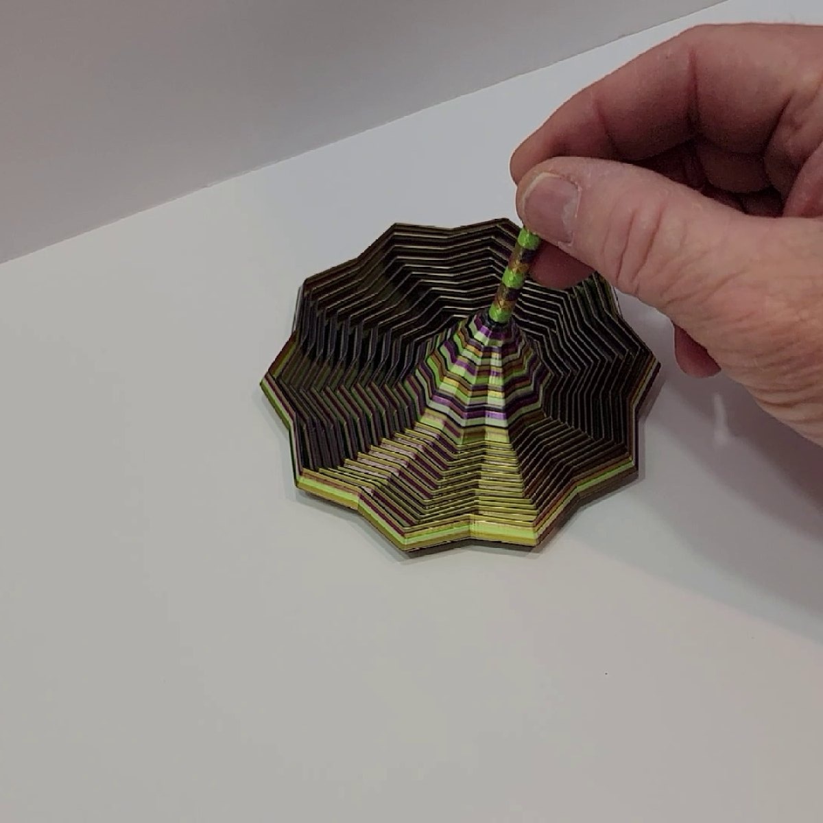 Top view of silk spiral sensory fidget in gold, purple, and green